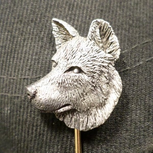 Op de afbeelding: Een zilveren wolfskop revers speld met een gouden speld. De wolfskop is gedetailleerd en realistisch.