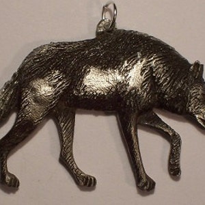 Op de afbeelding: Een wolf hanger van tin, met een gedetailleerd ontwerp en een zilveren lus om op te hangen.
