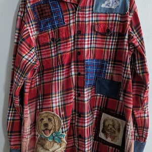 May include: Red and black plaid flannel shirt with various patches sewn on, including two dog patches, a denim patch, and a plaid patch. The shirt has a button-up front and long sleeves.