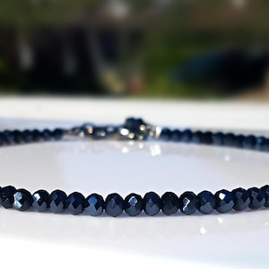 A delicate line of sparkly, dark blue faceted rondelle beads, beautifully catching the light, crafted into a bracelet that's perfect for both everyday wear and formal occasions.