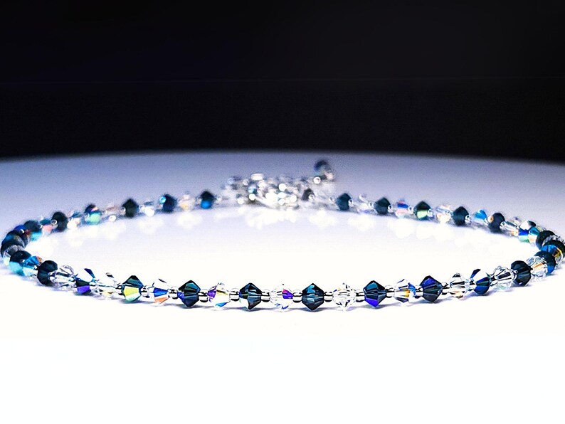 iridecent rainbow ab blue and clear interspersed bicone crystal necklace against a white background.