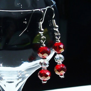 May include: A pair of silver dangle earrings with red and clear crystal beads.