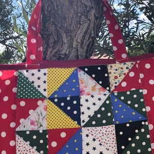 Pu&ograve; includere: Una borsa a tracolla rossa a pois bianchi con un design a patchwork che presenta vari tessuti con diversi motivi, tra cui stelle, pois e stampe floreali.