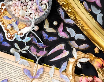 May include: A sheet of iridescent angel wing stickers with a pearl necklace and a book with text about turbine selection. The stickers are on a white background.
