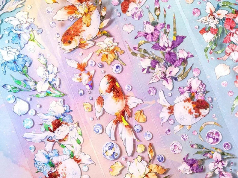 K&ouml;nnte beinhalten: Eine Bogen mit bunten Aufklebern mit Goldfischen und Blumen. Die Aufkleber befinden sich auf einem wei&szlig;en Hintergrund mit einem Regenbogeneffekt. Die Goldfische sind orange und wei&szlig; mit schwarzen Augen. Die Blumen sind lila, rosa und wei&szlig;.