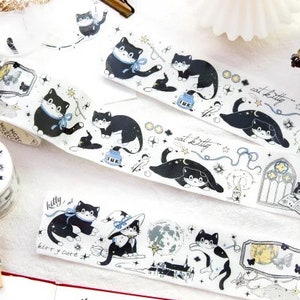 May include: Assortment of black and white washi tape rolls featuring a repeating pattern of cats, stars, and moons. The text on the tape reads "cat kitty" and "kitty and cat".
