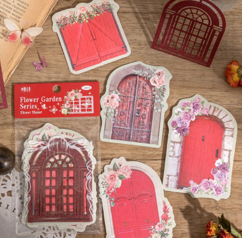May include: A pack of six decorative door stickers featuring various styles of doors with floral accents. The stickers are printed on a white background and have a vintage aesthetic. The pack includes a sticker with the text "Flower Garden Series, Flower Manor".