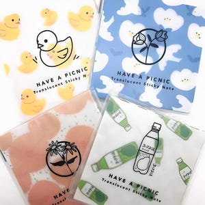 Może przedstawiać: Cztery opakowania przezroczystych karteczek samoprzylepnych z różnymi wzorami. Każde opakowanie ma białe tło z powtarzającym się wzorem żółtych kurcząt, chmur, kwiatów lub zielonych butelek. Na każdym opakowaniu znajduje się napis "HAVE A PICNIC" i "Translucent Sticky Note".
