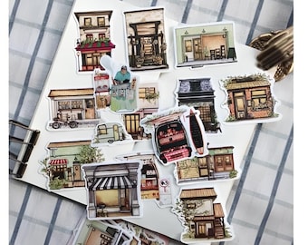May include: A set of 14 colorful stickers featuring illustrations of various shops and storefronts. The stickers are printed on white paper and have a glossy finish.