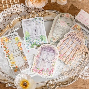 May include: A set of decorative stickers featuring vintage-style doors and windows with floral accents. The stickers are printed on white paper and have a delicate, romantic aesthetic. The text on the sticker reads "Flower Garden Series - Many Joint Stickers".