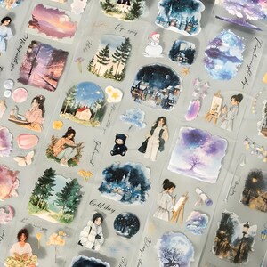 May include: A sheet of decorative stickers featuring watercolor illustrations. Designs include landscapes, figures, and celestial elements in shades of blue, purple, and pink. Some stickers have text.