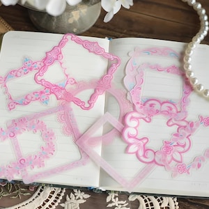 May include: Pink decorative paper frames with floral designs. The frames are perfect for scrapbooking, journaling, or adding a touch of whimsy to your crafts.