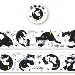 May include: A white washi tape with black and white illustrations of cats, stars, moons, and other celestial elements. The text "kitty cute" appears twice on the tape. The tape is packaged on a roll with a round sticker that says "kitty cute" in English and Japanese.