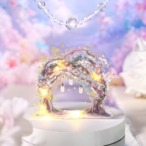 May include: A decorative tree arch with warm LED lights, set on a white base. The arch features a detailed illustration of a tree with hanging lanterns and star accents. The background has a soft, dreamy, pastel color scheme.
