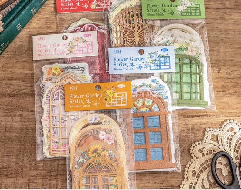 May include: A set of decorative window stickers in a clear plastic bag. The stickers are printed with a floral design and have a vintage aesthetic. The stickers are labeled "Flower Garden Series" with different sub-series names like "Sunshine Garden", "Dream Traveler", "Moon Flower Shade", "Distant Islands", and "Flower Manor".