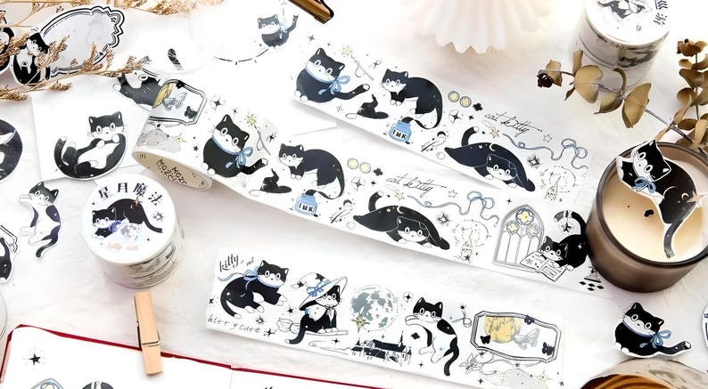 May include: A set of washi tape featuring black cats with stars, moons, and other whimsical designs. The tape is on a white background and comes in a variety of patterns.