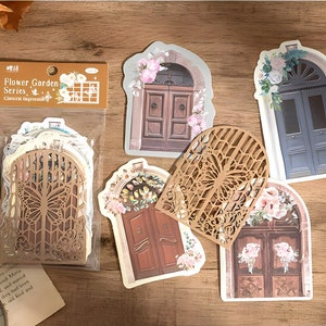 May include: A set of decorative stickers featuring various ornate doors with floral accents. The stickers are part of a "Flower Garden Series" and are designed for crafting and scrapbooking.