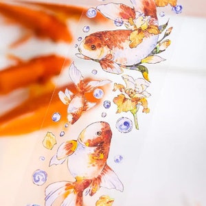 K&ouml;nnte beinhalten: Ein dekoratives Washi-Tape mit einem Aquarell-Design von Goldfischen, die zwischen zarten Blumen und Blasen schwimmen. Das Band ist transparent und hat einen wei&szlig;en Hintergrund.