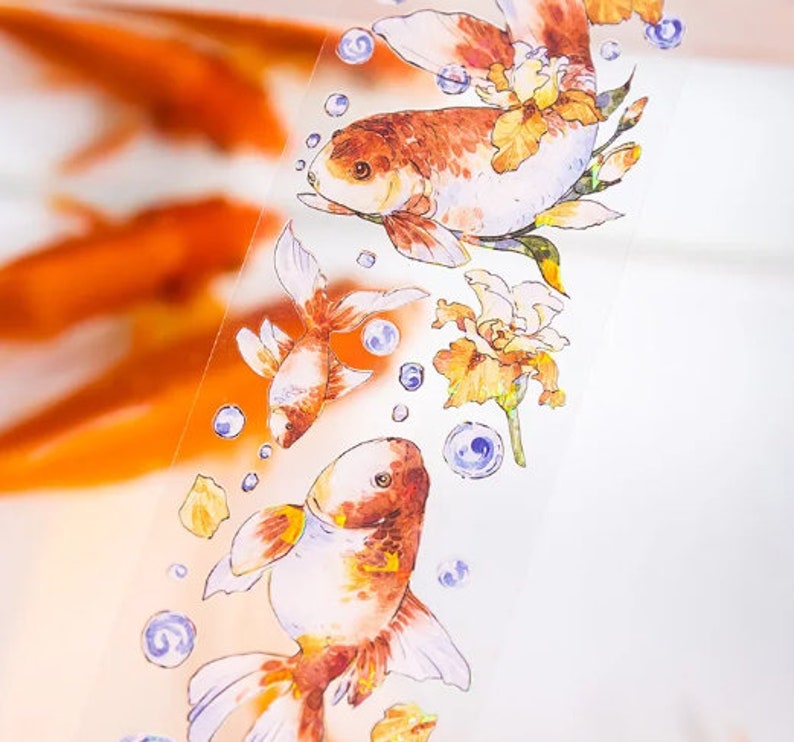 K&ouml;nnte beinhalten: Ein dekoratives Washi-Tape mit einem Aquarell-Design von Goldfischen, die zwischen zarten Blumen und Blasen schwimmen. Das Band ist transparent und hat einen wei&szlig;en Hintergrund.