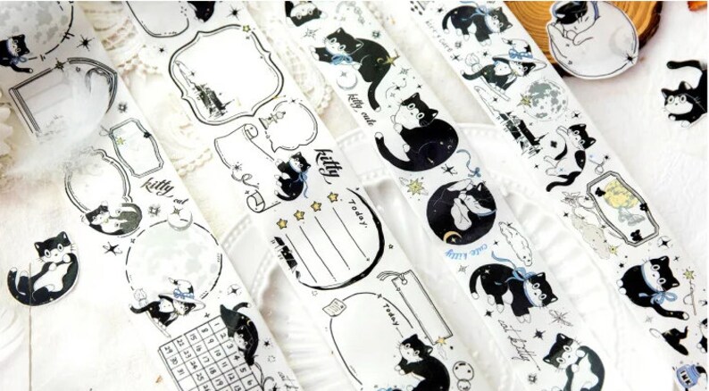 May include: Five rolls of black and white washi tape featuring cute black cats, stars, moons, and other whimsical designs. The tape is perfect for decorating planners, journals, and other paper crafts.