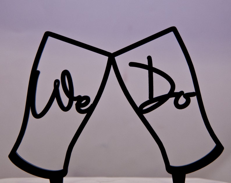 A laser cut wedding cake topper painted in your choice of color. The wedding cake topper is two guinness beer glasses toasting with We Do inside the glasses