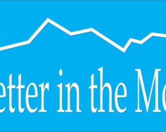 May include: White text on a blue background reads "Life's Better in the Mountains". A white mountain range silhouette is above the text.