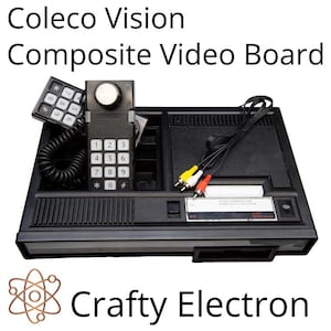 Peut inclure: Une carte vidéo composite Coleco Vision noire avec un clavier, un joystick et divers ports. La console porte les inscriptions "Coleco Vision Composite Video Board" et "Crafty Electron".