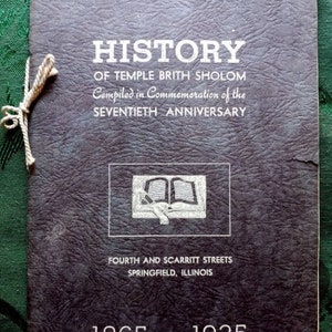May include: A black leather-bound book with the title "HISTORY OF TEMPLE BRITH SHOLOM" and the text "Compiled in Commemoration of the SEVENTIETH ANNIVERSARY" in white lettering. The book also includes the text "FOURTH AND SCARRITT STREETS SPRINGFIELD, ILLINOIS 1865---1935".