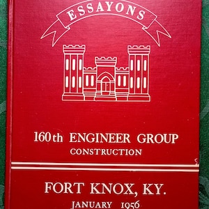 May include: A red book cover with white text and a white illustration of a castle. The text reads "ESSAYONS" above the illustration, and "160th ENGINEER GROUP CONSTRUCTION" and "FORT KNOX, KY. JANUARY 1956" below.