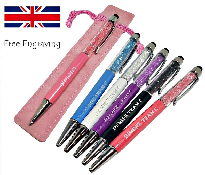 May include: A collection of colorful pens with crystal-filled barrels and touch screen tips. Each pen is engraved with a name and the text "TEAM C". A pink pen case and the text "Free Engraving" are also visible.