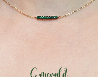 May include: A delicate gold chain necklace with a bar of emerald green beads. The necklace is on a model's neck.  Emerald.