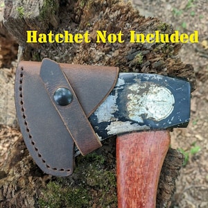 May include: A brown leather sheath with a snap closure for a hatchet. The sheath is attached to a hatchet with a wooden handle. "Hatchet Not Included" is written in yellow text at the top of the image.