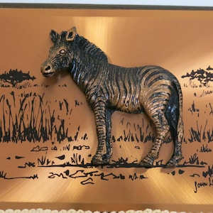 Könnte beinhalten: Eine 3D-Kupferplatte mit einer schwarzen und weißen Zebra-Skulptur auf kupferfarbenem Hintergrund. Das Zebra steht in einem Grasfeld mit Bäumen im Hintergrund. Die Platte ist mit "John Lewis" signiert.