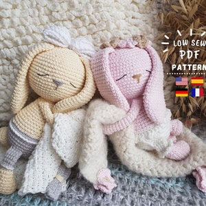 May include: Two crocheted bunny amigurumi toys, one pink and one cream, are lying down on a white blanket. The bunnies have closed eyes and are holding a white blanket. The text "Low Sew PDF Pattern" is visible in the image.