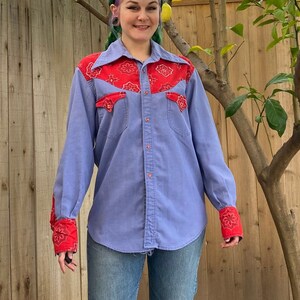 1970’s men’s western long sleeve shirt. Blue with red bandana print details on collar, pockets and cuffs. Pearl snaps down the front and on sleeves. Fits like a men’s medium