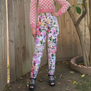 1990s white denim jeans with pink, purple and yellow floral print all over. High waisted skinny jeans with loops at the bottom of the legs for your feet. Size XS/ Small.