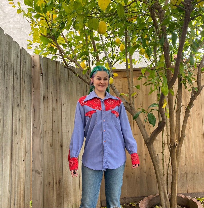 1970’s men’s western long sleeve shirt. Blue with red bandana print details on collar, pockets and cuffs. Pearl snaps down the front and on sleeves. Fits like a men’s medium