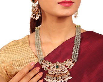 May include: A gold necklace with a green stone pendant and pearl accents. The necklace is made of multiple strands of light green beads. The pendant features a floral design with intricate details.