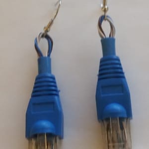 Pode incluir: Um par de brincos de conector Ethernet azul. Os conectores são presos a ganchos prateados.