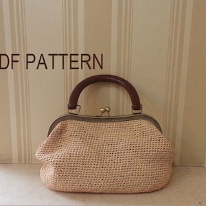 May include: A beige crocheted handbag with a brown wooden handle and a brass clasp. The bag is sitting on a striped background.  PDF PATTERN