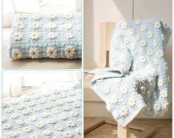 May include: A light blue crocheted blanket with a daisy pattern. The blanket is folded and draped over a chair.