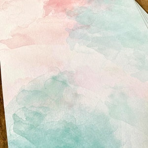 Peut inclure: Une feuille de papier aquarelle avec une lavis aquarelle rose clair et vert. Le lavis est irr&eacute;gulier et a un aspect doux et fondu.