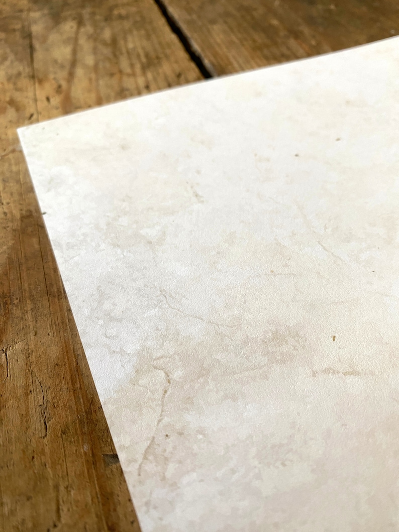 May include: A close-up of a light beige tile with a subtle marbled pattern. The tile has a smooth, slightly textured surface.