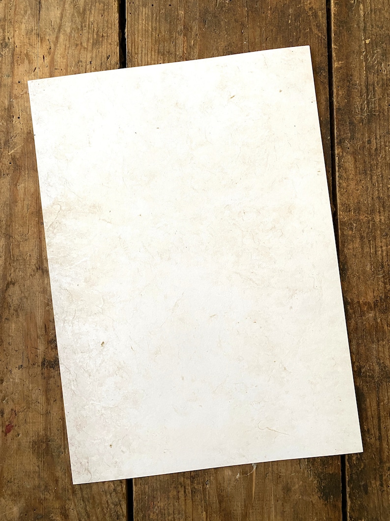 May include: A blank sheet of white paper with a slightly textured surface, lying on a wooden surface.