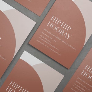 Puede incluir: Una colecci&oacute;n de invitaciones de color terracota con un dise&ntilde;o semicircular en blanco y beige claro. El texto "HIP HIP HOORAY" se muestra de forma destacada, junto con los detalles del evento. Las invitaciones est&aacute;n dispuestas sobre una superficie gris.