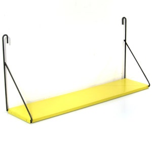 May include: A wall-mounted shelf with a bright yellow rectangular surface. The shelf is supported by black metal brackets that hook over the top and angle down to the shelf. The shelf is designed for displaying items or storage.