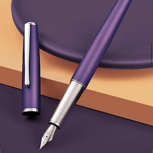 May include: A purple fountain pen with a silver nib and accents. The pen's cap is detached and placed next to the pen. The background is a gradient of purple and brown.
