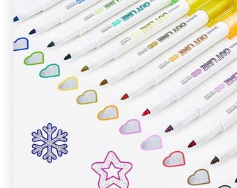 May include: A set of eight markers with white barrels and colored caps, labeled OUT LINE MARKER. The markers are arranged diagonally, each paired with a corresponding hand-drawn shape like a snowflake, heart, or star in matching ink colors.