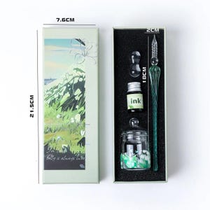 K&ouml;nnte beinhalten: Ein Kalligraphie-Set in einer Geschenkbox. Das Set enth&auml;lt einen gr&uuml;nen Glas-Dip-Pen (18cm), eine Tintenflasche, ein Tintenfass und einen kleinen Glas-Tintenhalter. Die Box ist 21,5cm hoch und 7,6cm breit, mit floralem Design und dem Text "Folly is always sweet."