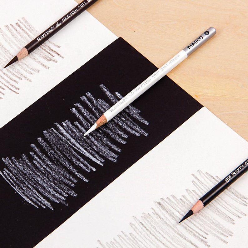 May include: Close-up of three drawing pencils on a white and black striped surface. The pencils are labelled "RAFINE" and "MARCO".